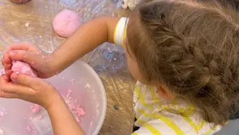 Dziecko wygniatające masę na kulkę do kąpieli