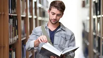 Student z książką na tle regałów z książkami