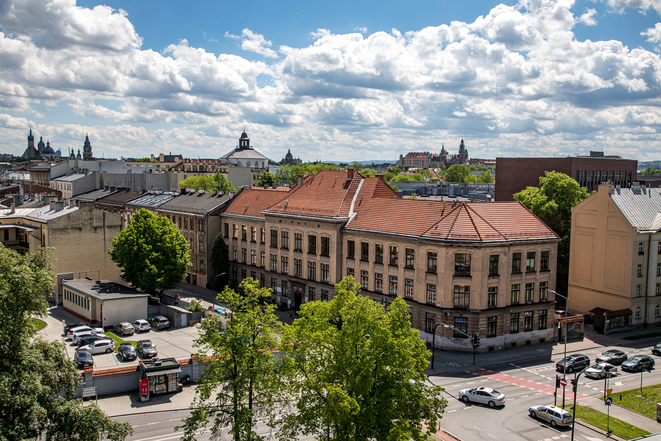 Panorama Krakowa. Odnowione stare kamieniczki na tle zamku na Wawelu oraz białych chmur.