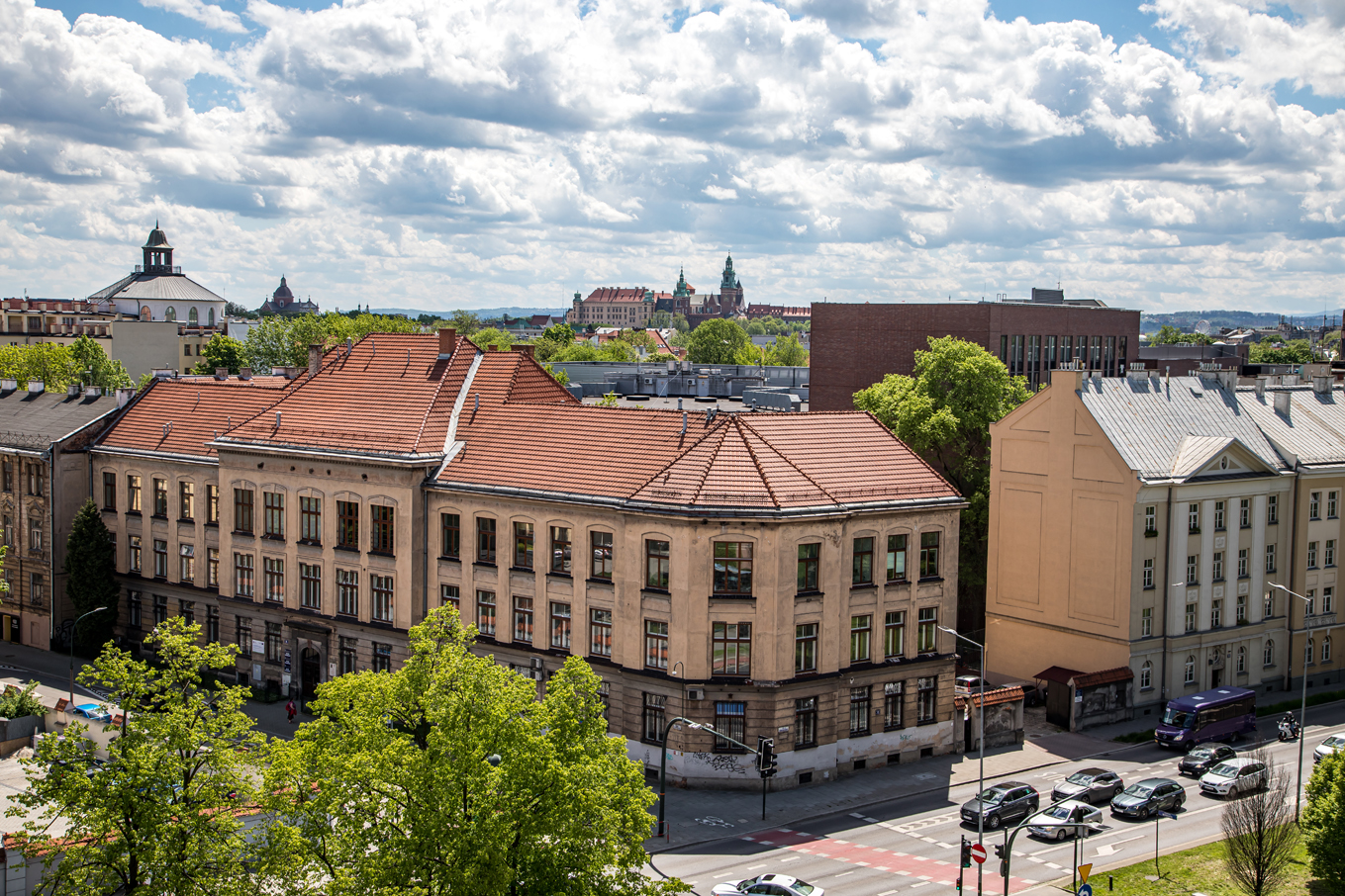 Panorama Krakowa. Odnowione stare kamieniczki na tle zamku na Wawelu oraz białych chmur.