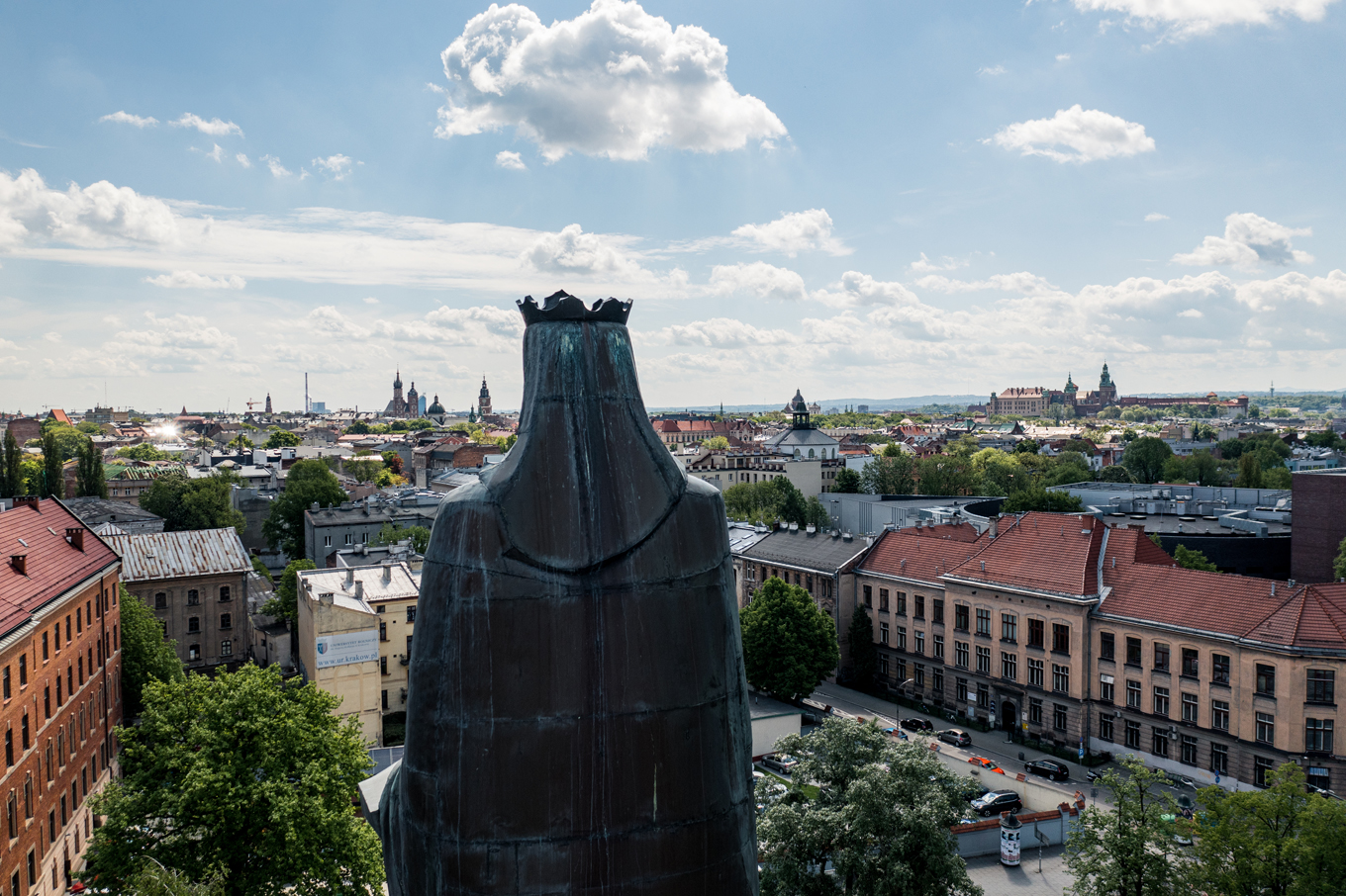 Pomnik Św Barbary spoglądający na panoramę Krakowa. W tle widać stare kamieniczki. Po prawej Wawel. Po lewej Kościół Mariacki.