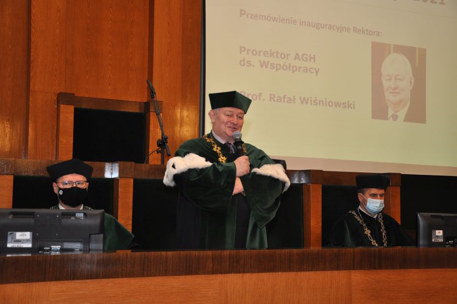 Prorektor ds. Współpracy, prof. Rafał Wiśniowski ubrany w uroczystą togę przemawia stojąc za drewnianego pulpitu na środku auli A0