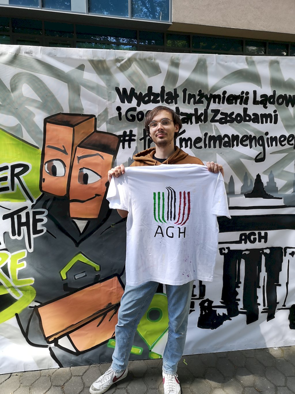 Student prezentuje koszulkę z namalowanym logo AGH.