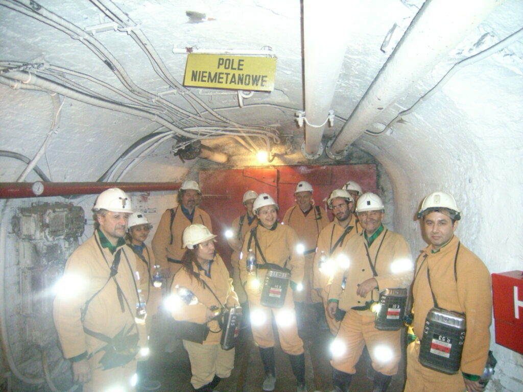 Górnicy w kaskach z lampami w korytarzu