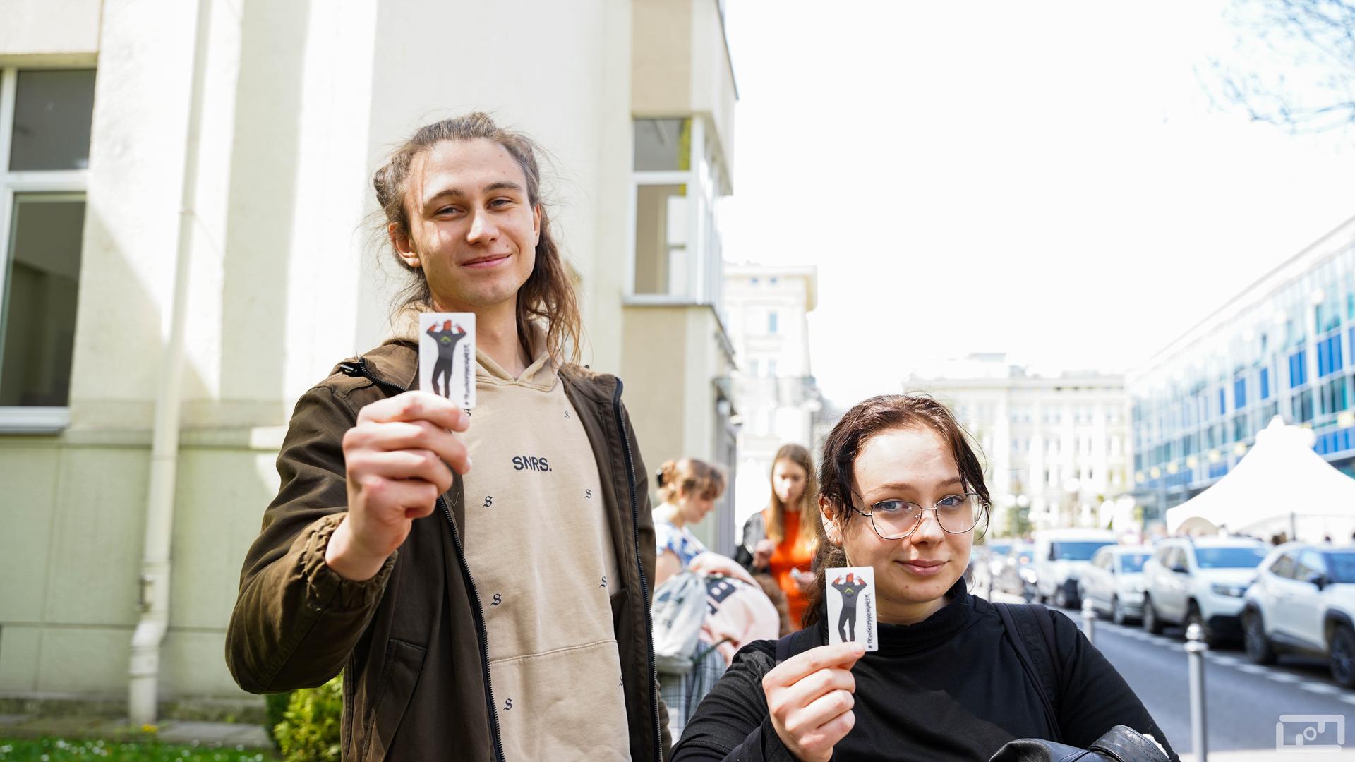 Na zdjęciu widać studentkę i studenta trzymających naklejkę z ceglakiem podczas Dni Otwartych AGH 2023.