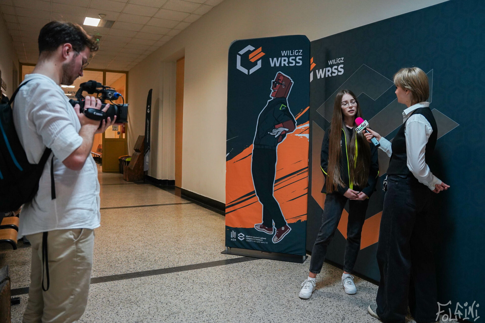 Na zdjęciu widać studentkę WILiGZ ubraną w bluzę wydziałową udzielającą wydziału podczas akcji Biustowniczki i Mosznowładcy. W tle znajduje się ścianka WILiGZ WRSS.